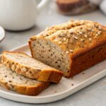 Sliced oatmeal and chia bread topped with seeds on a white plate.